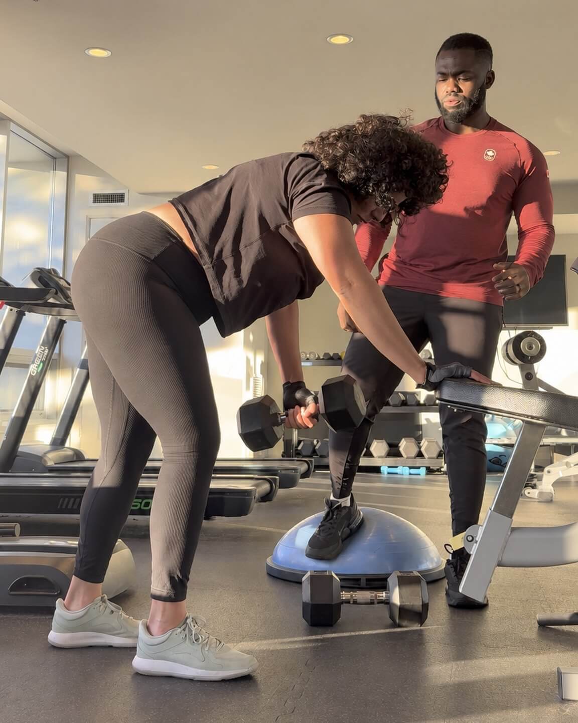 Doug watching a client's form as she rows a dumbbell.