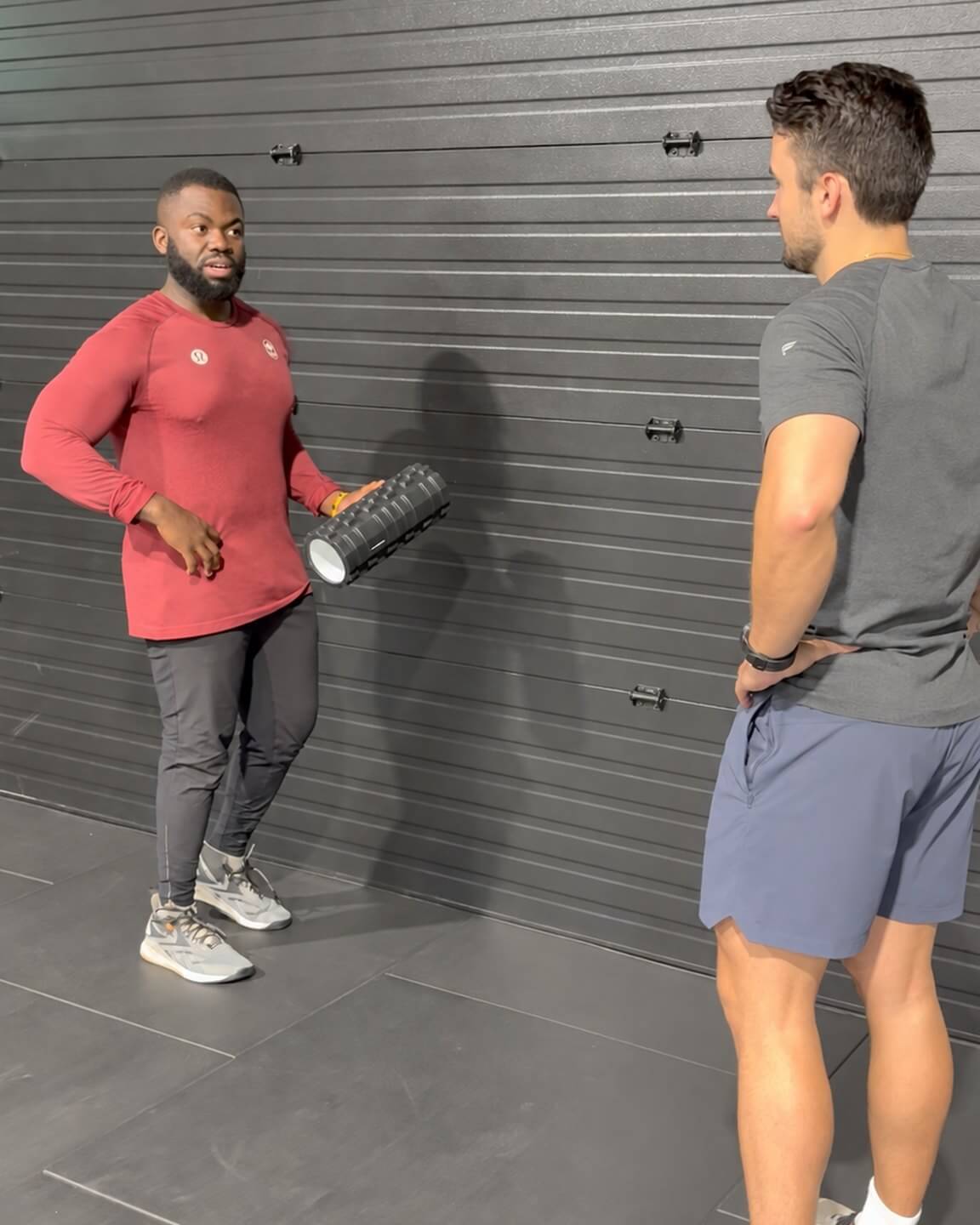 Doug talking a client through a stretch, foam roller in hand.