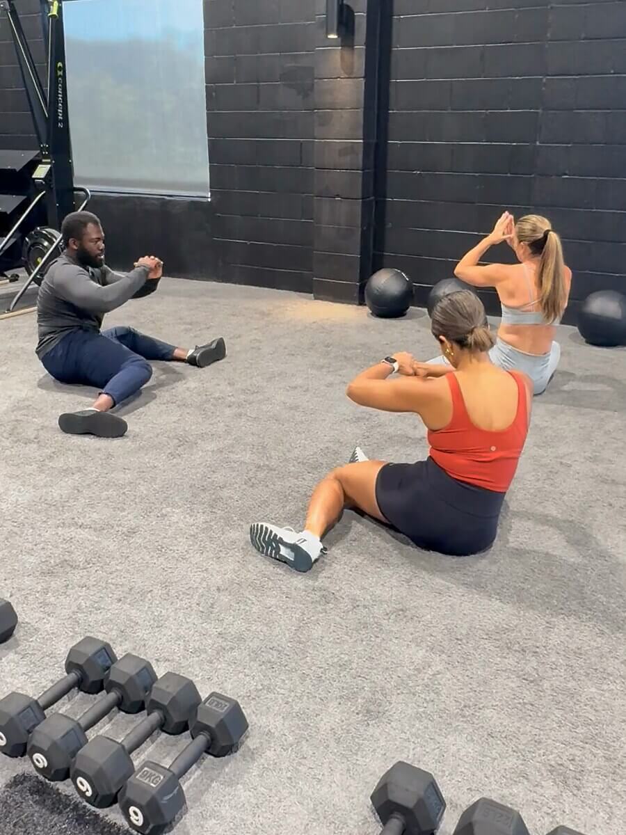 Doug coaching two clients on the mats at the gym.